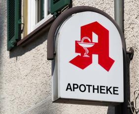 Schild an Hauswand mit Apotheken-Logo